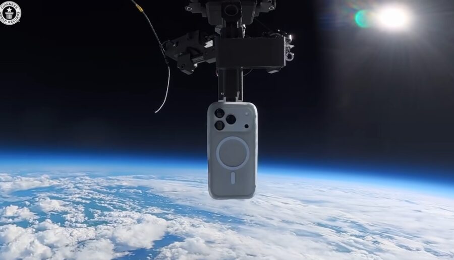 Ein silbernes Smartphone ist an einem schwarzen Kamerahalter befestigt und schwebt über der Erde im Weltraum.