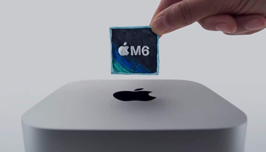 Eine Hand hält einen Apple M6 Chip über einem silbernen Apple-Computer.